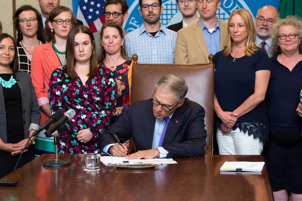 Gov Inslee signing the Solar Jobs Bill. Alana Nelson of FMS in white pants.