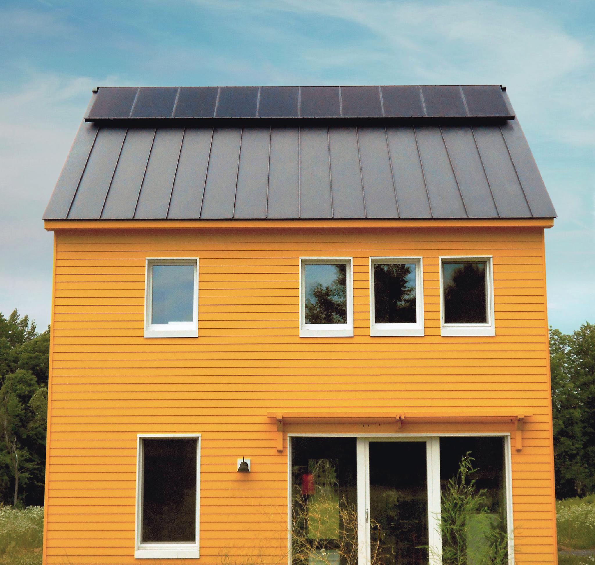 All-black SunPower solar panels on small yellow home with passive solar in Amherst, Massachusetts